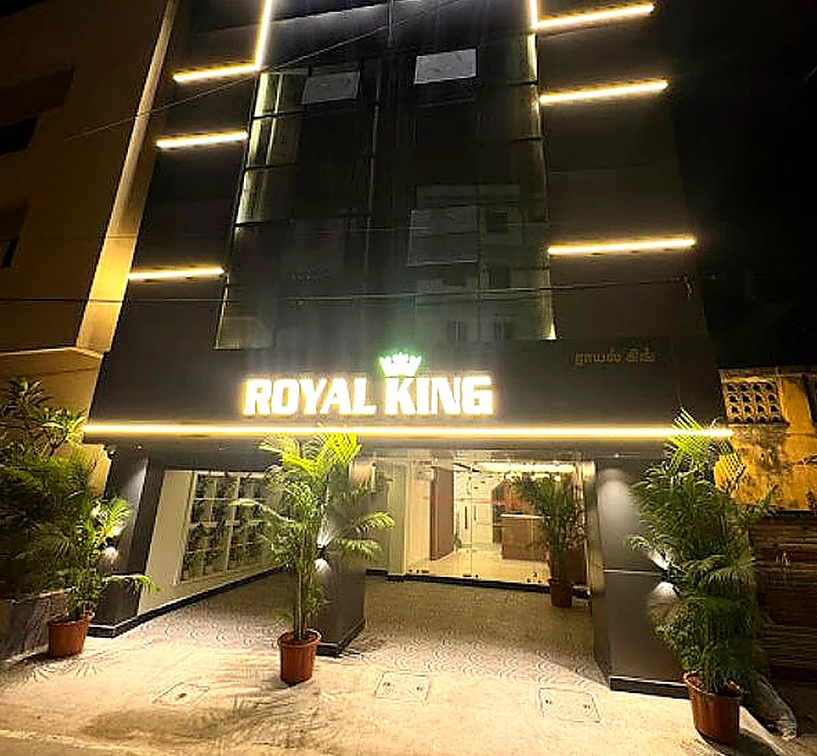 Hotel Royal King frontage at night, with gold light lines on a black facade